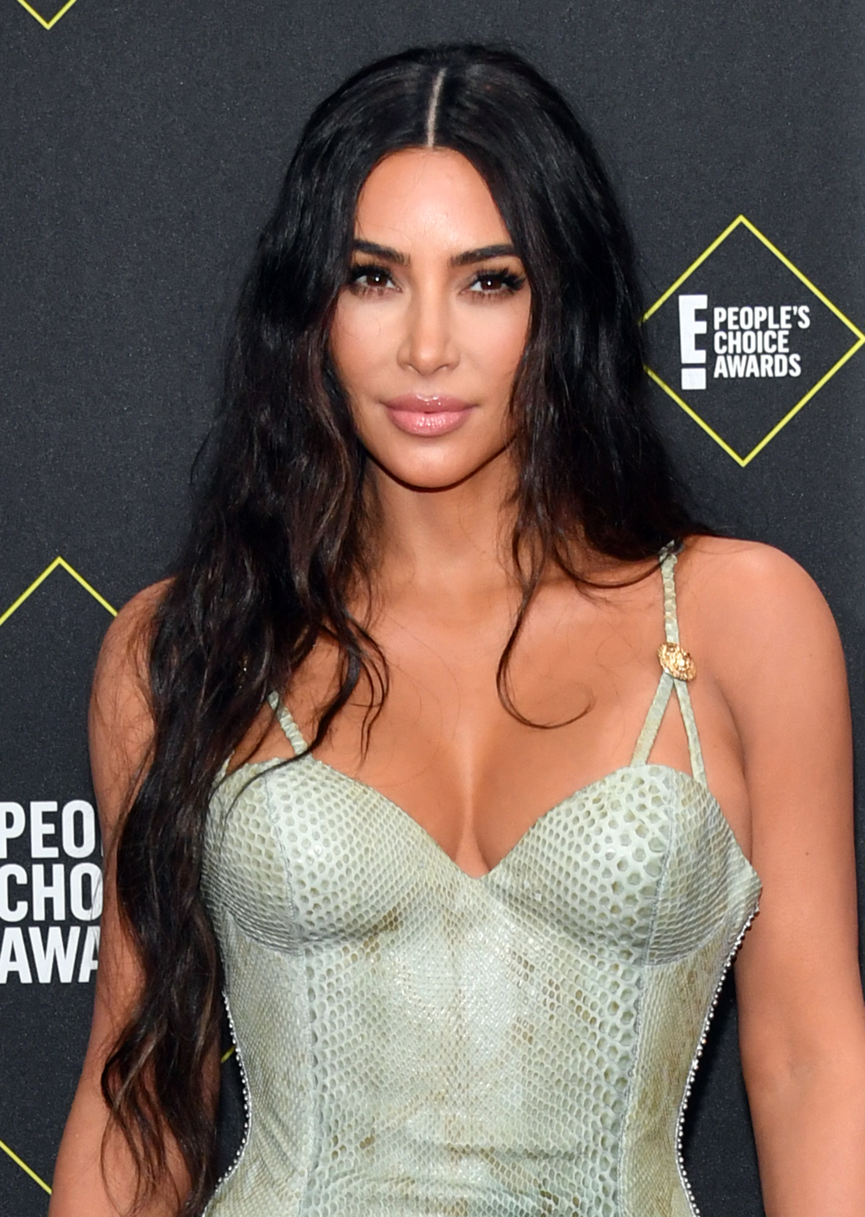 Kim Kardashian at People's Choice Awards in a fitted, patterned dress with spaghetti straps and long, wavy hair