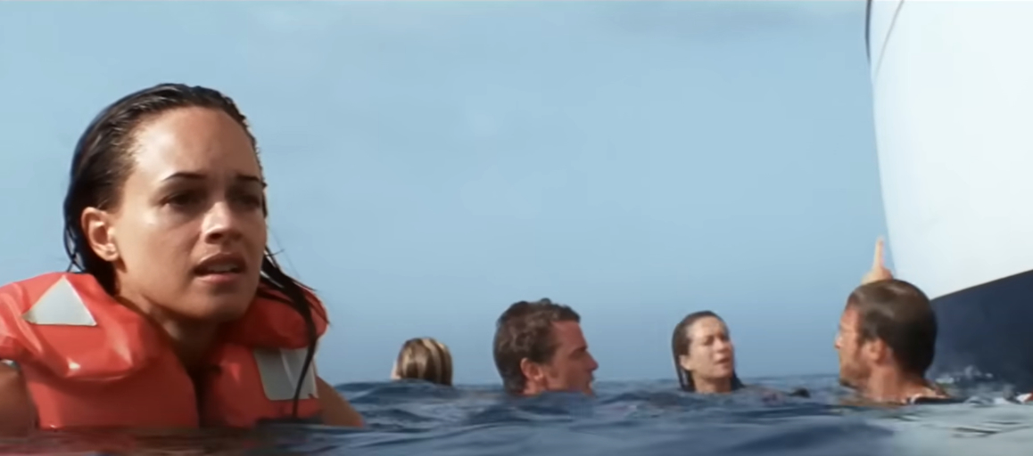 A woman in a life jacket and several others swim near a boat in open water