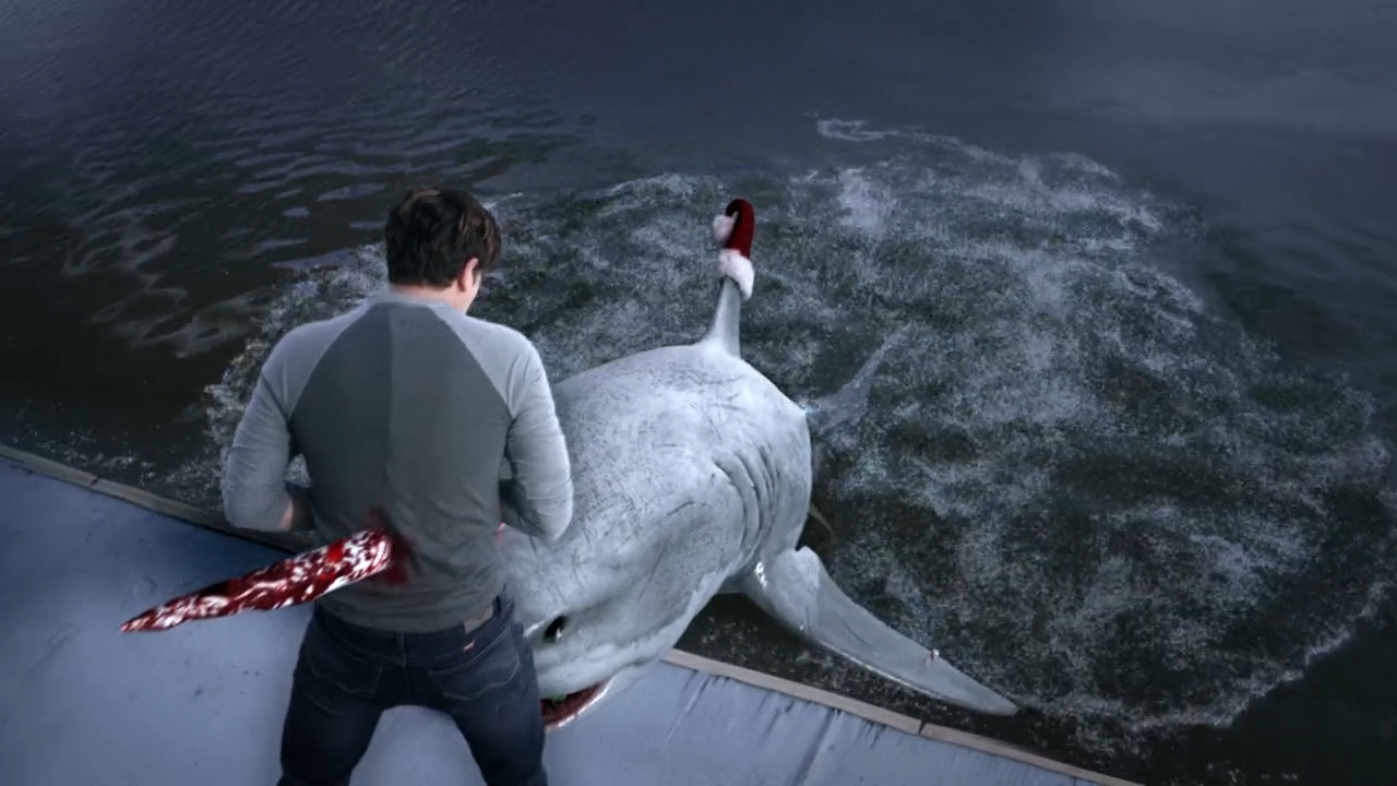A man, seen from behind, fights off an attacking shark at the edge of a water body.