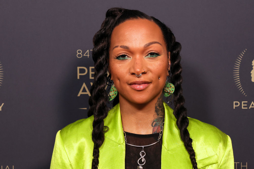 Kali Reis posing at a Peabody Awards event, wearing a vibrant outfit with bold makeup and jewelry