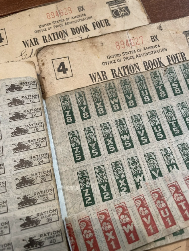 World War II-era U.S. War Ration Books with various stamps; one is titled "War Ration Book Four" from the Office of Price Administration