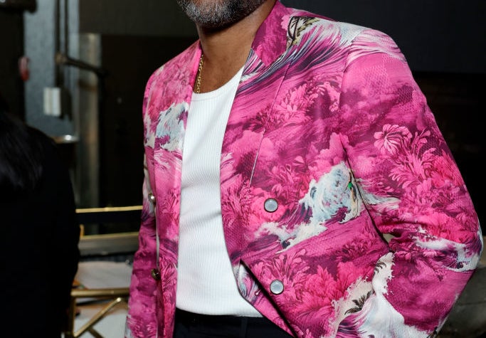 Donald Glover wearing a vibrant patterned blazer over a white shirt, standing in a well-lit room