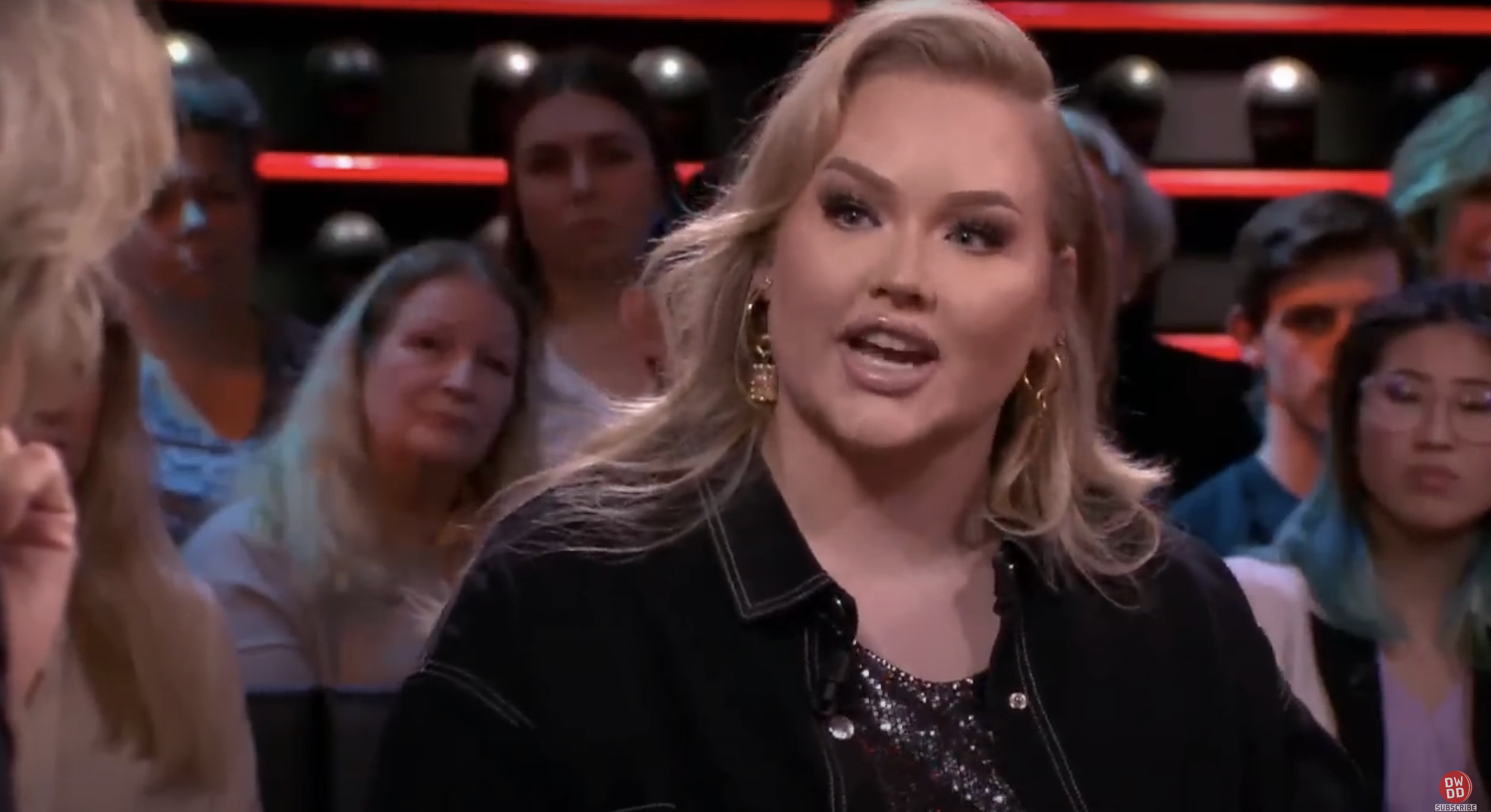 Nikkie de Jager speaks passionately on a TV show panel, with audience members paying close attention in the background