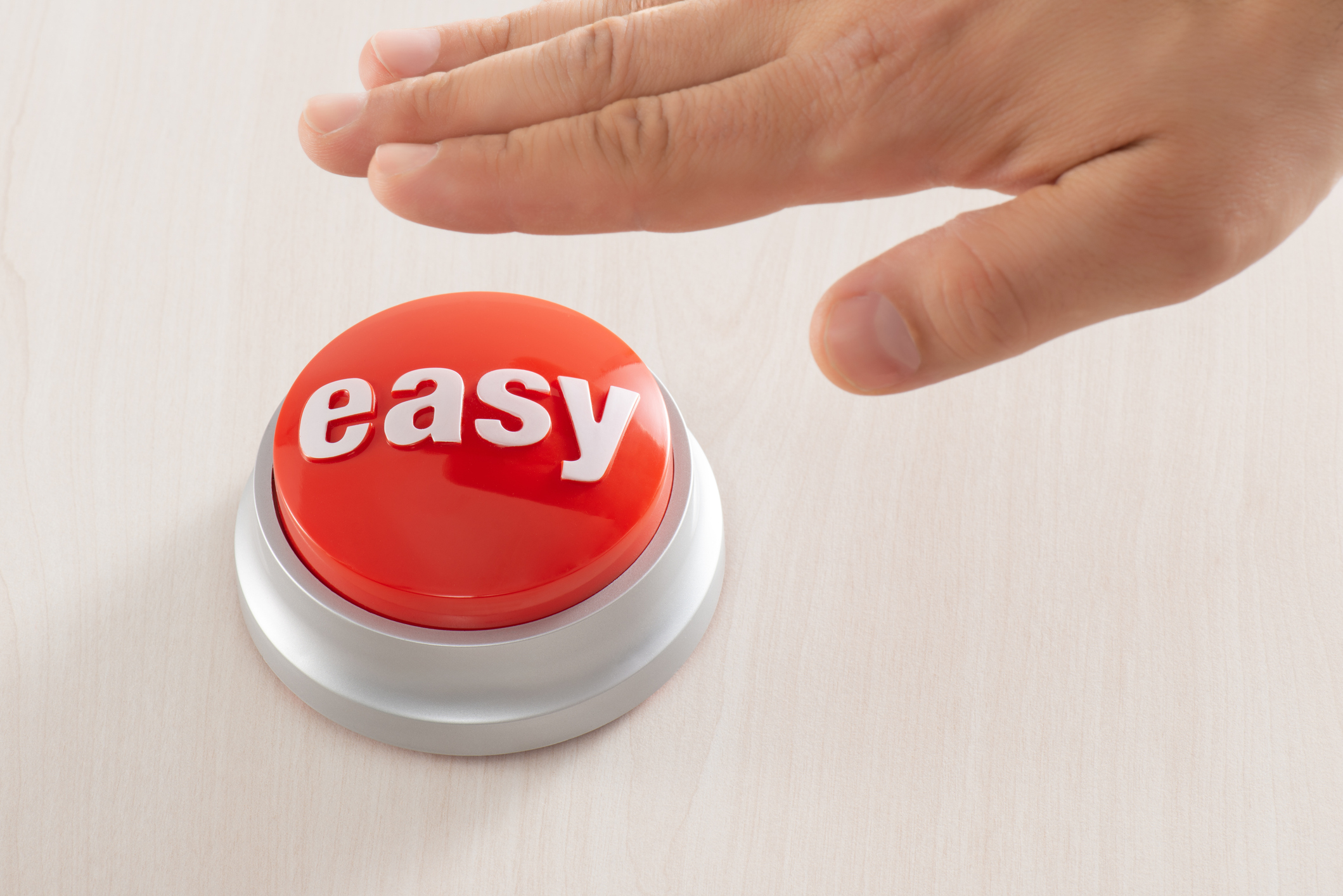 A hand reaches to press a red button labeled "easy" on a light wooden table