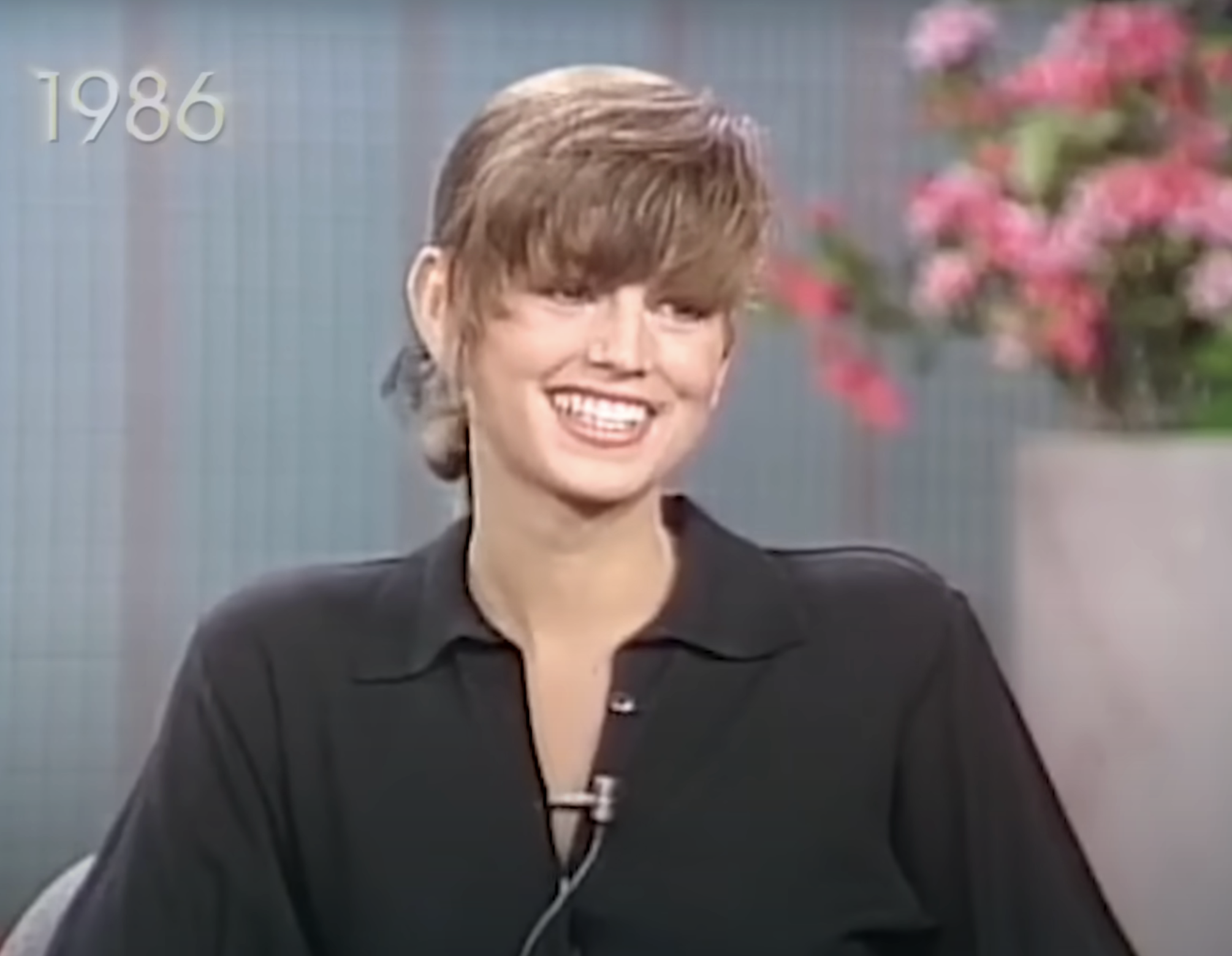 Young Cindy, smiling with short hair, wearing a dark blouse.