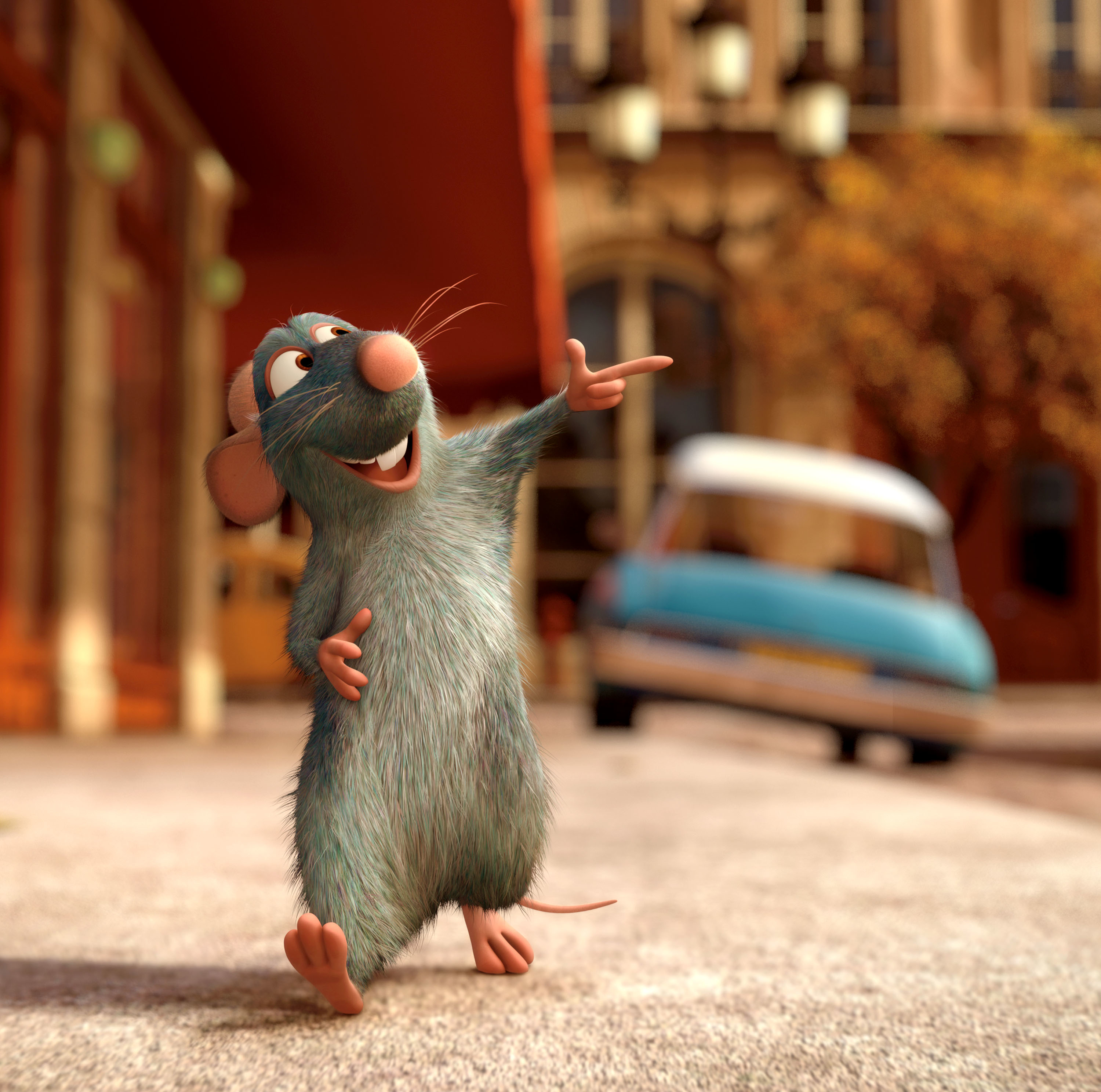 Remy, the rat from "Ratatouille," joyfully gestures while standing on a city street with a blurry car and buildings in the background