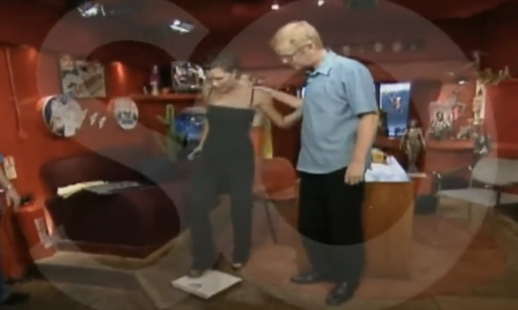 Chris helps Victoria step onto a scale on set