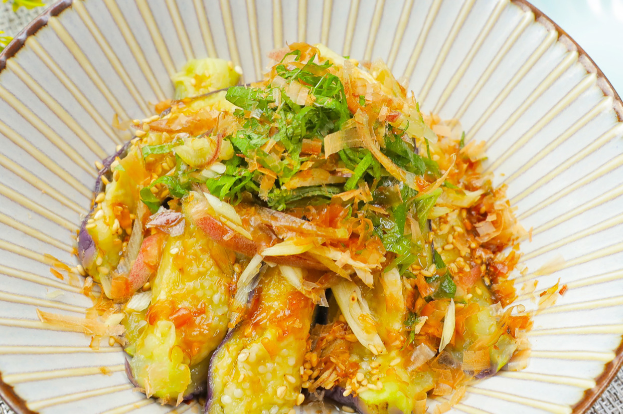お皿に盛られた茄子と薬味の和風サラダ。薬味はみょうがと大葉、ゴマが散りばめられている。