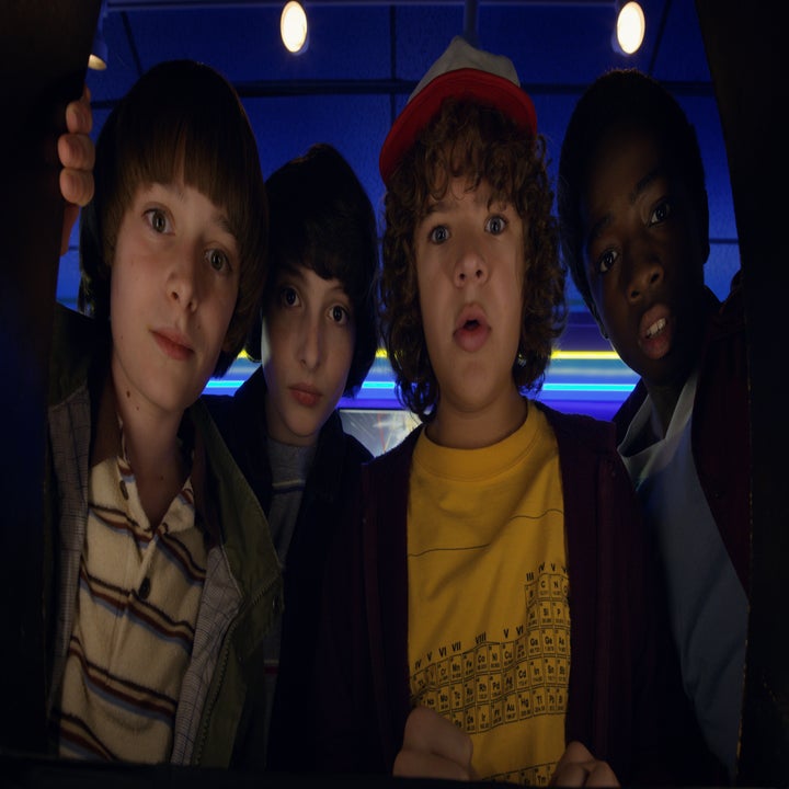 Noah Schnapp, Finn Wolfhard, Gaten Matarazzo, and Caleb McLaughlin from Stranger Things looking surprised while peering down at something