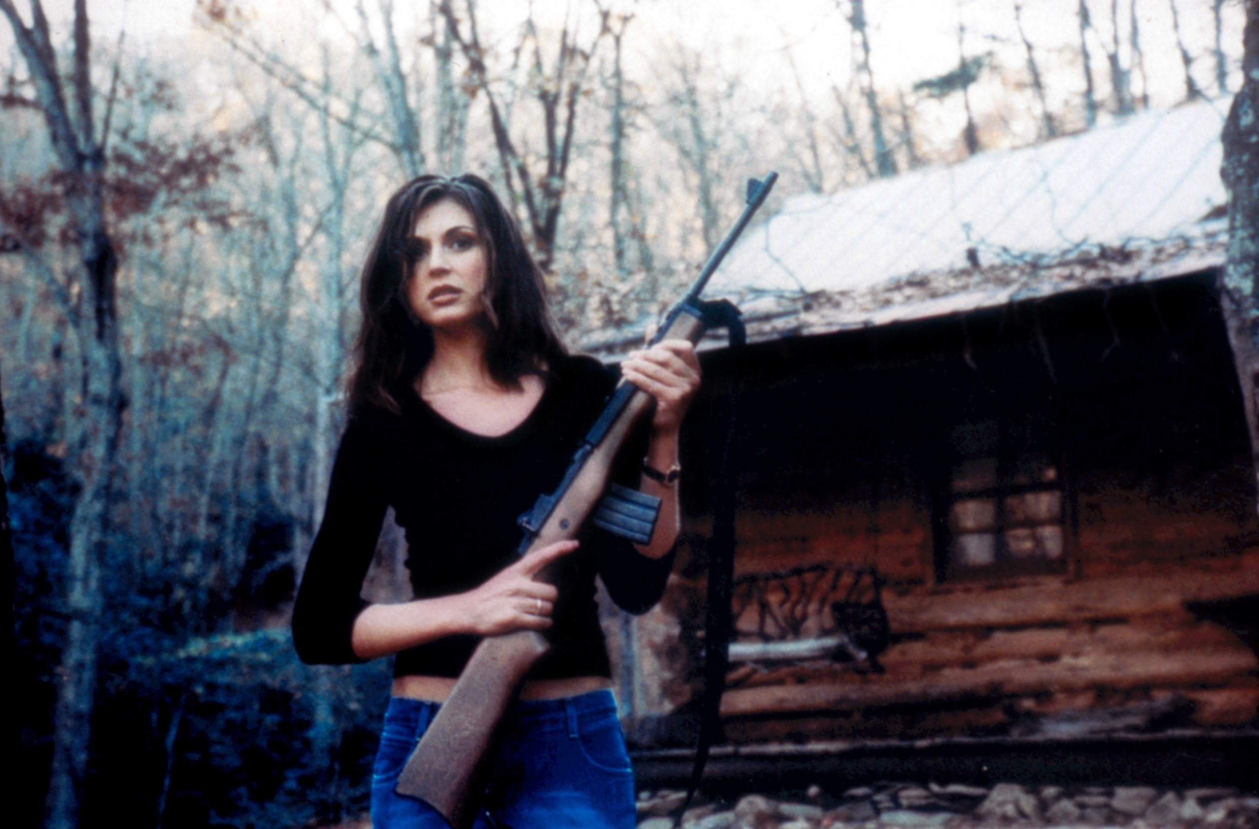 Cerina Vincent holding a shotgun outside of a rustic cabin in a scene from &quot;Cabin Fever&quot;