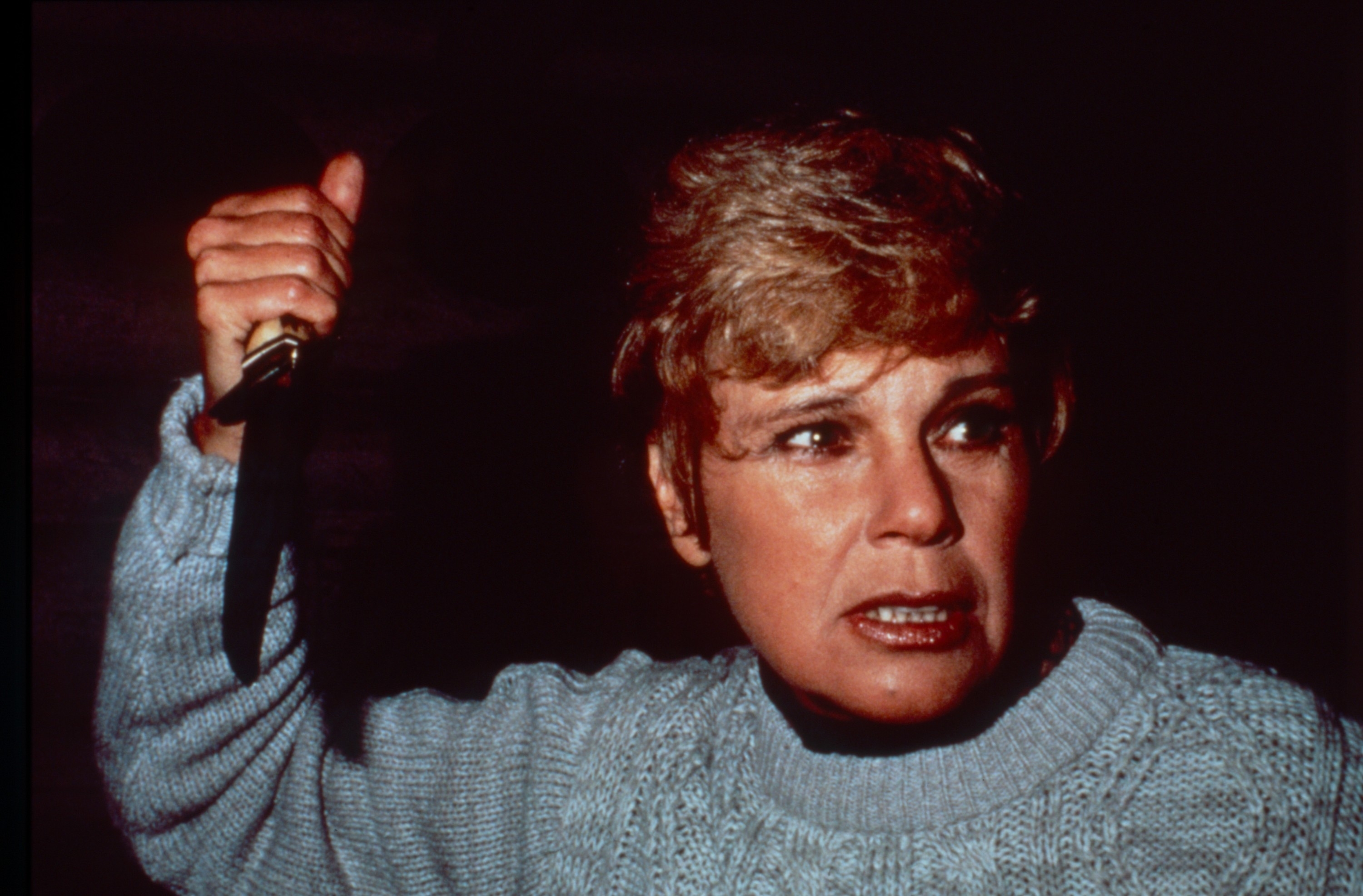Betsy Palmer holding a knife, looking intense, dressed in a cozy sweater in a scene from &quot;Friday the 13th&quot;