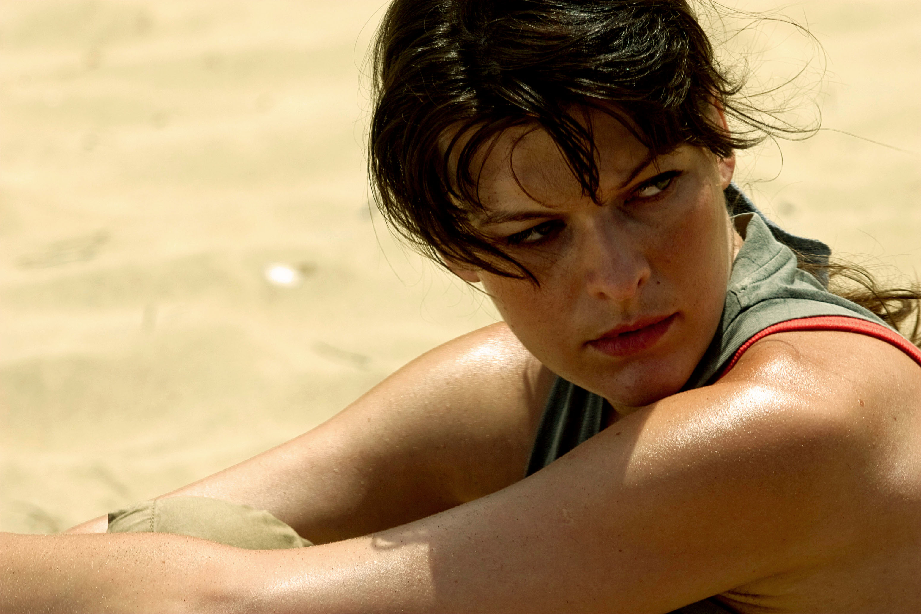Milla Jovovich sits on a sandy beach in a scene from &quot;A Perfect Getaway&quot;