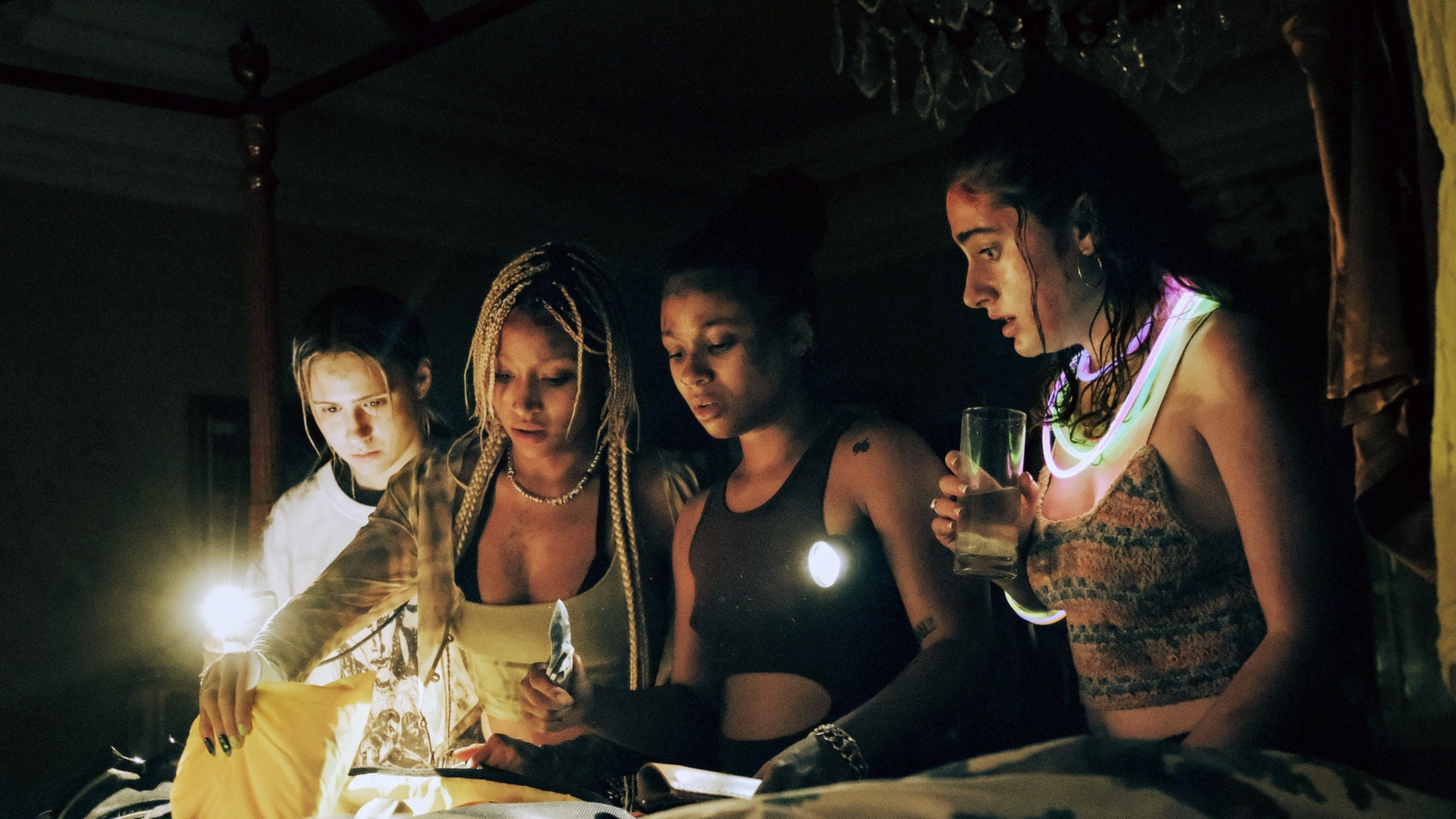Maria Bakalova, Amandla Stenberg, Myha'la Herrold, and Rachel Sennott looking at something while holding flashlights in a scene from &quot;Bodies Bodies Bodies&quot;