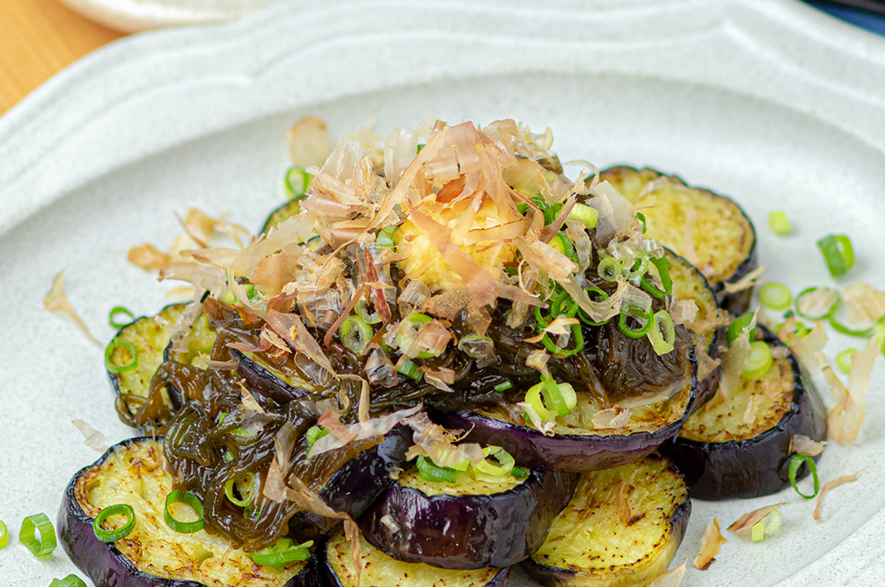 皿に盛られた焼きナスに刻みネギと鰹節がかかった料理。