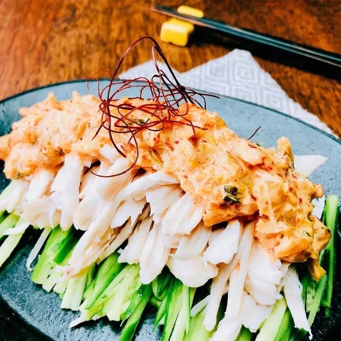 きゅうりの上にのったカニの肉と辛いソース。箸とナプキンが背景にあります。