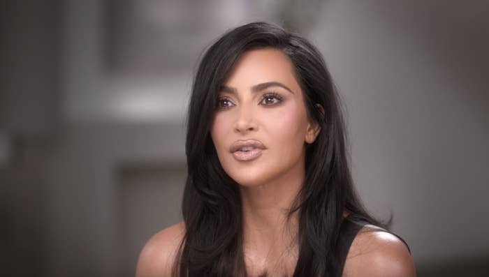 Kim Kardashian in a close-up shot, looking slightly off-camera with a neutral expression and wearing a simple, sleeveless top