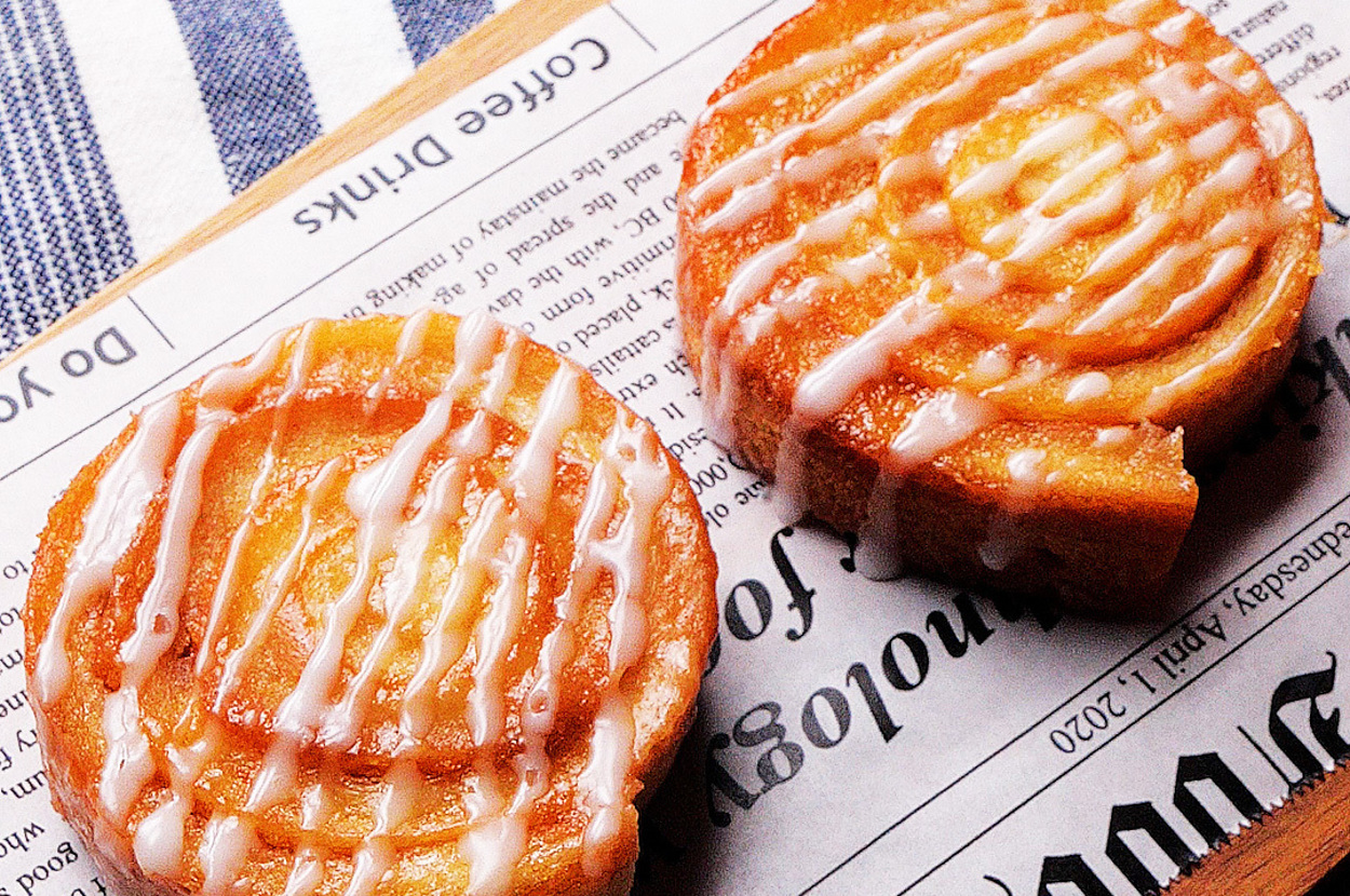 新聞紙の上に置かれた2つのアイシングがかかったパン。