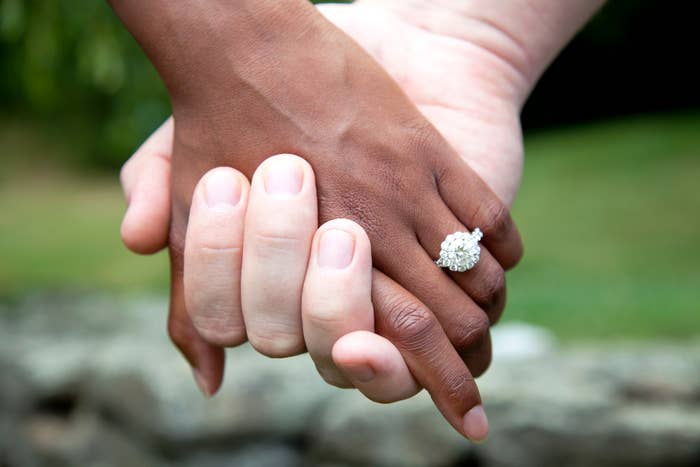 Close-up of two hands holding, one with a diamond engagement ring