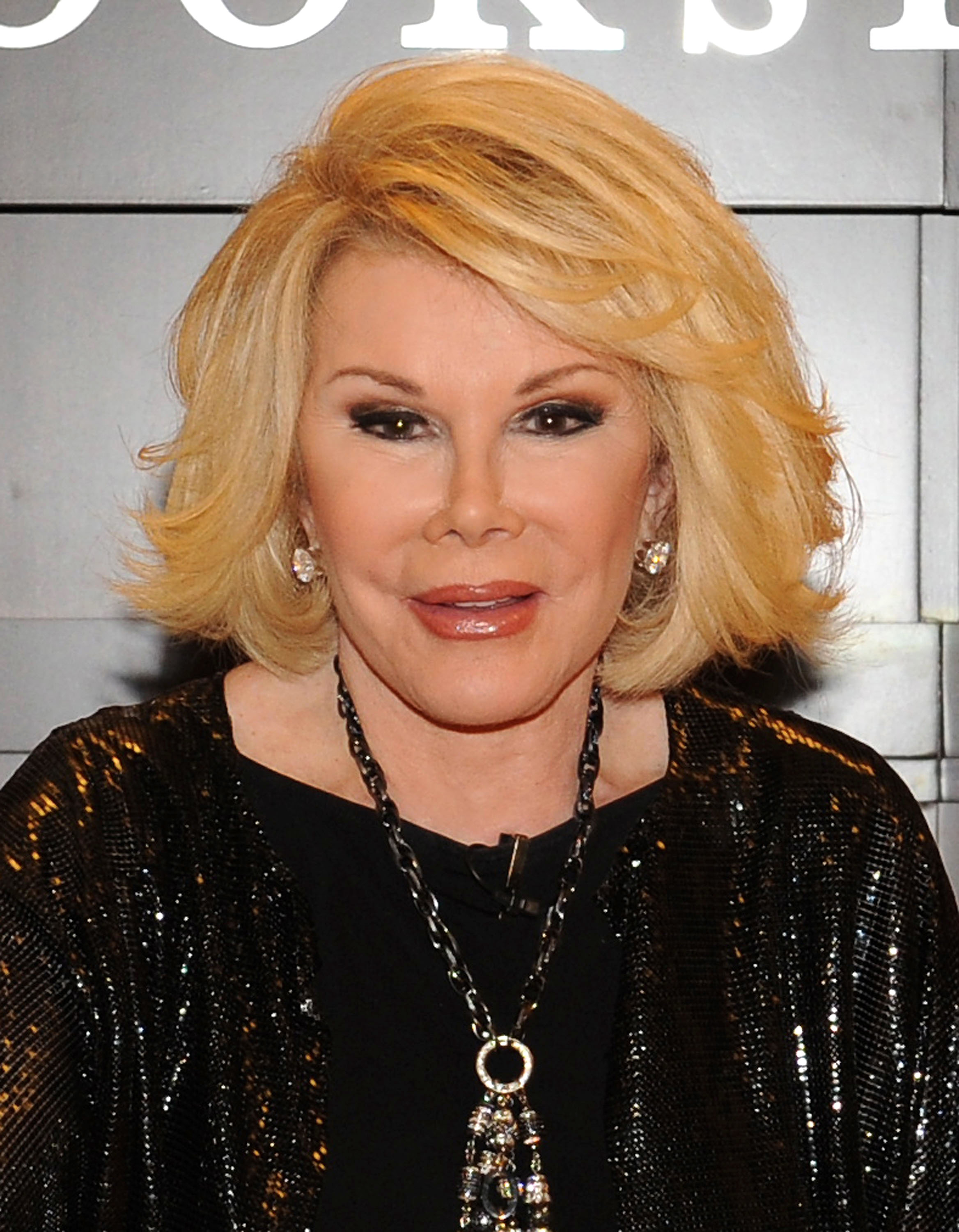 Joan Rivers wearing a black sequined jacket with a statement necklace