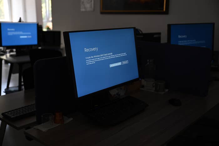 Several desktop computers in a dimly lit office display a blue "Recovery" screen indicating that Windows did not start correctly