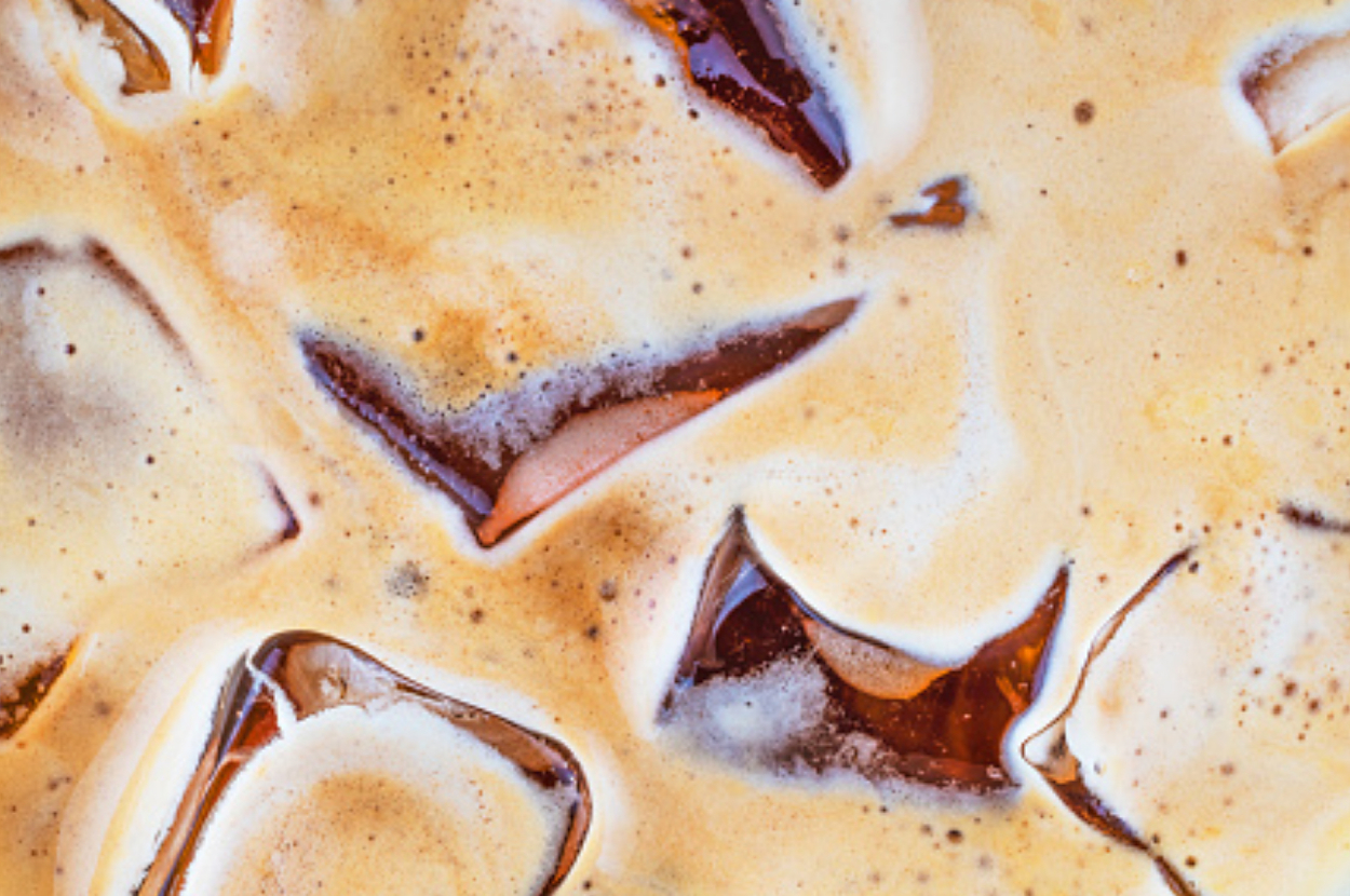 Close-up view of iced coffee with ice cubes floating in creamy coffee