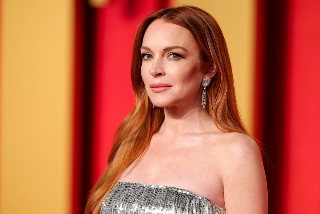 Lindsay Lohan on the red carpet, wearing a strapless metallic dress and long earrings, with her hair down