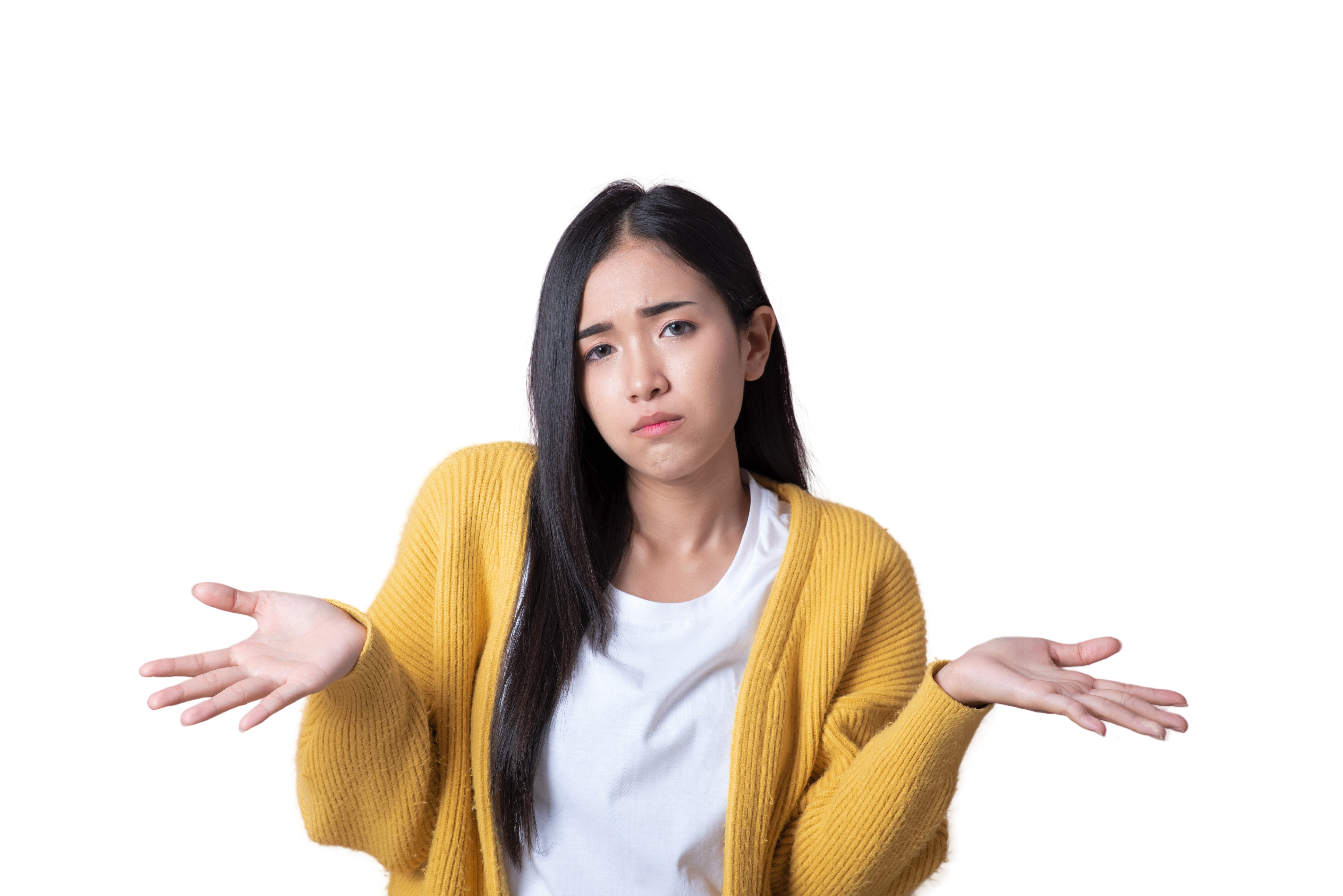 A woman with long hair in a white shirt and yellow cardigan shrugs with her hands up, looking confused or unsure against a plain background