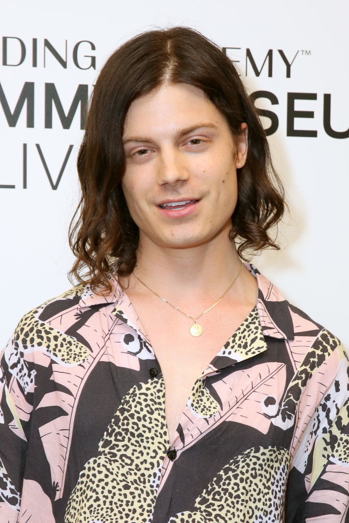 Barns Courtney at a red carpet event, wearing a patterned shirt with abstract designs and a pendant necklace