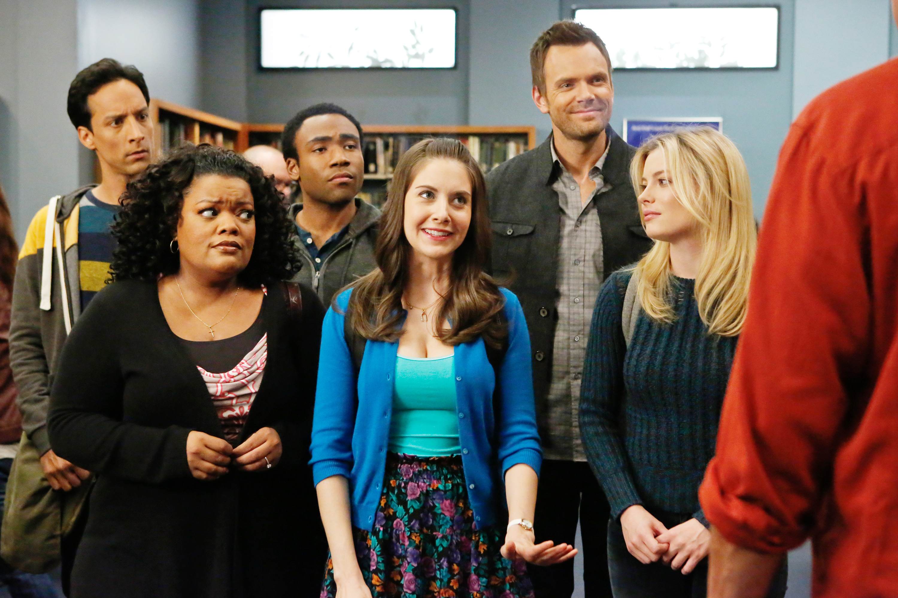 Yvette Nicole Brown, Danny Pudi, Donald Glover, Alison Brie, Joel McHale, and Gillian Jacobs stand together, looking at someone off-camera in a staged scene