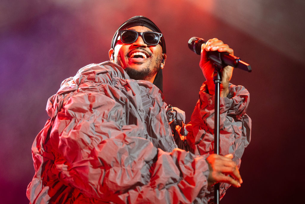 Ray J performs on stage, wearing sunglasses and a puffy jacket while singing into a microphone