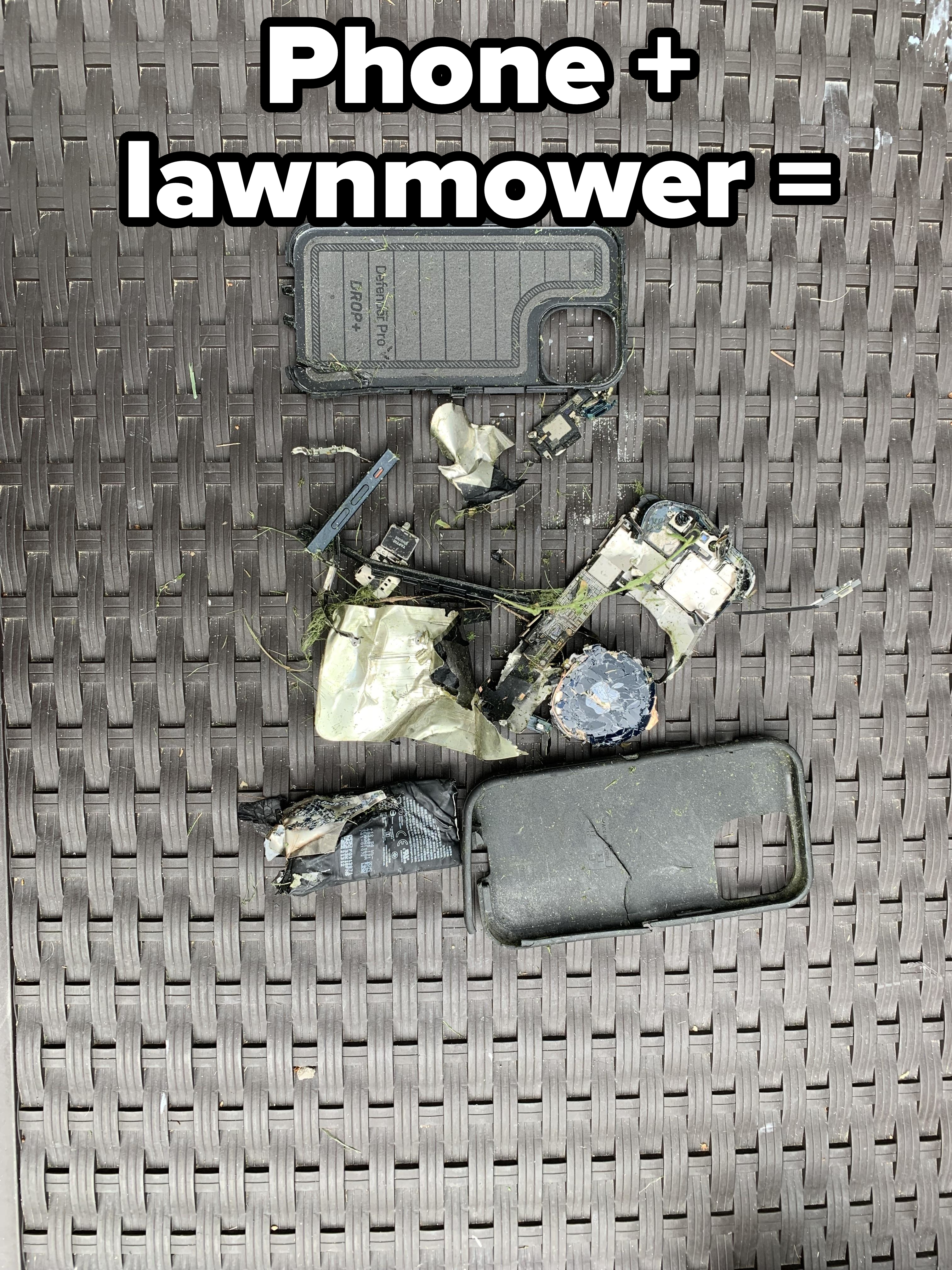 The image shows a disassembled and damaged phone with various broken parts spread out on a wicker surface