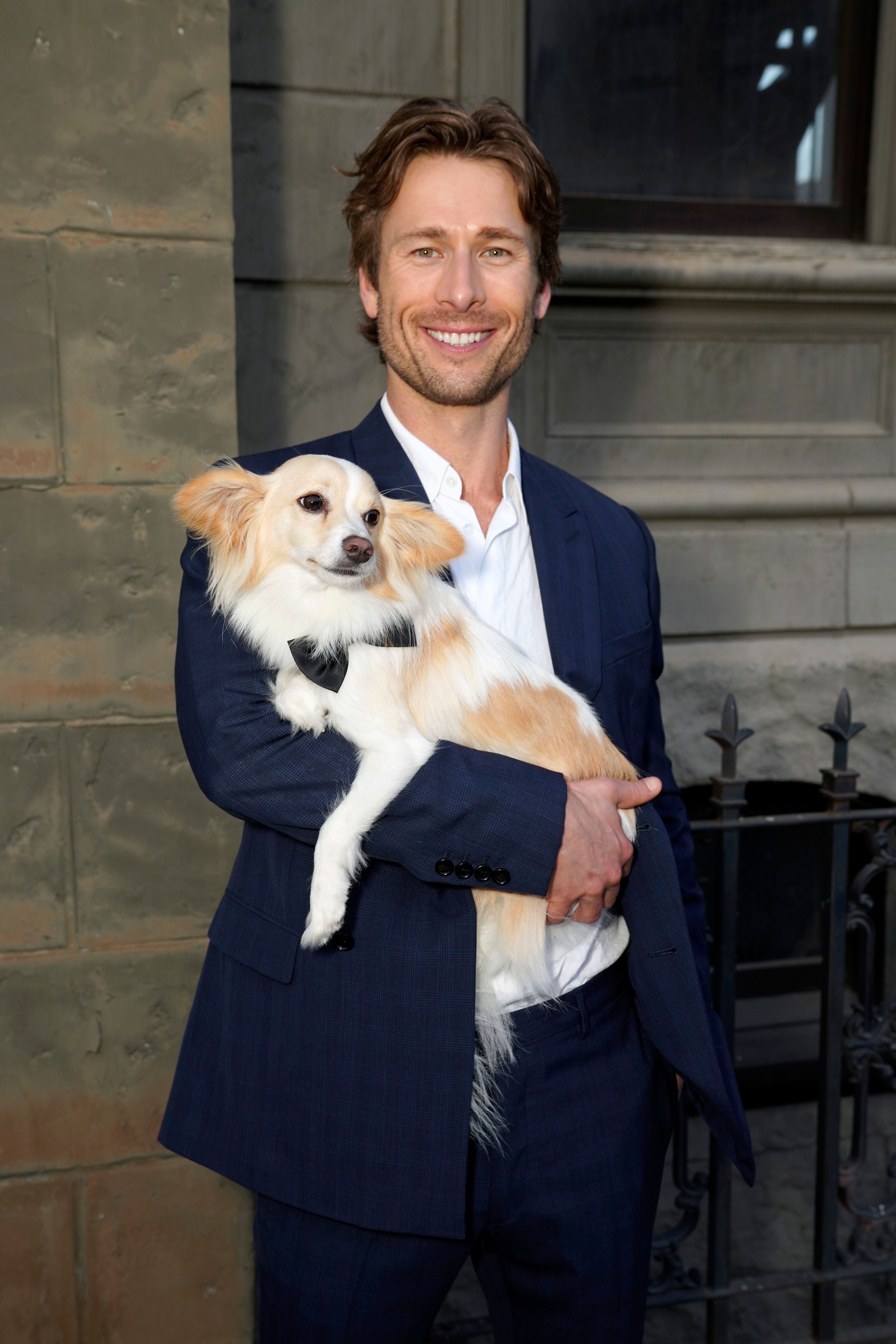 Glen Powell holding his dog Brisket at an event