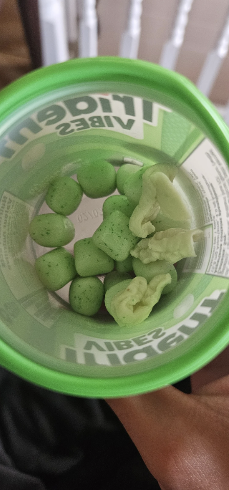 A container of Trident Vibes gum, showing several mint-flavored gum pieces and a few distorted, melted-looking pieces among them