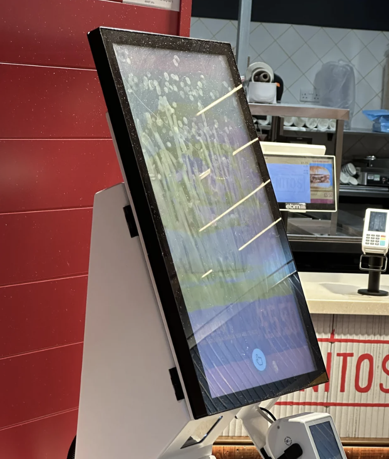 Touchscreen ordering kiosk at a fast-food restaurant with condensation on the display