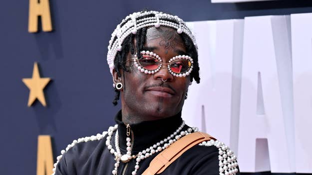 Lil Uzi Vert on the red carpet, wearing a black outfit adorned with pearls, and large, embellished glasses