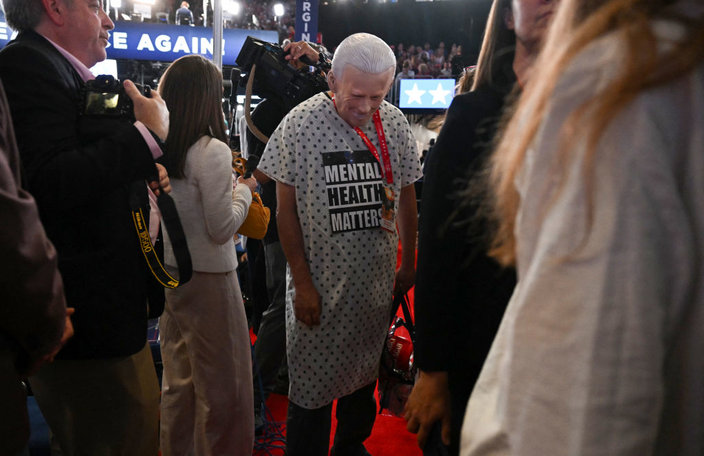 Person wearing a &quot;Mental Health Matters&quot; shirt stands among crowd on a red carpet at an event. Various others are around, taking photos and mingling