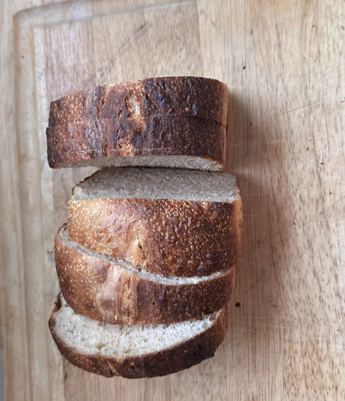 Three slices of bread, evenly stacked on a wooden cutting board