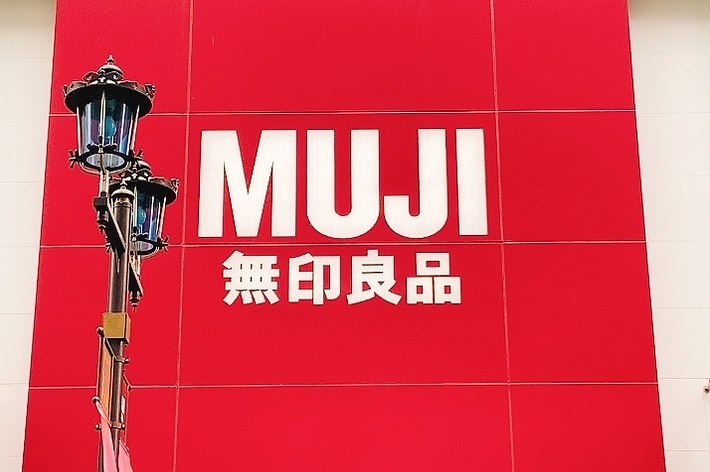 MUJIの店舗前にある大型の赤い看板に「MUJI 無印良品」と書かれている。