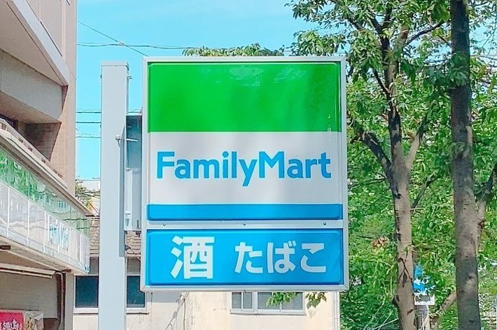 ファミリーマートの看板と周囲の街並み。酒とたばこの販売も表示。