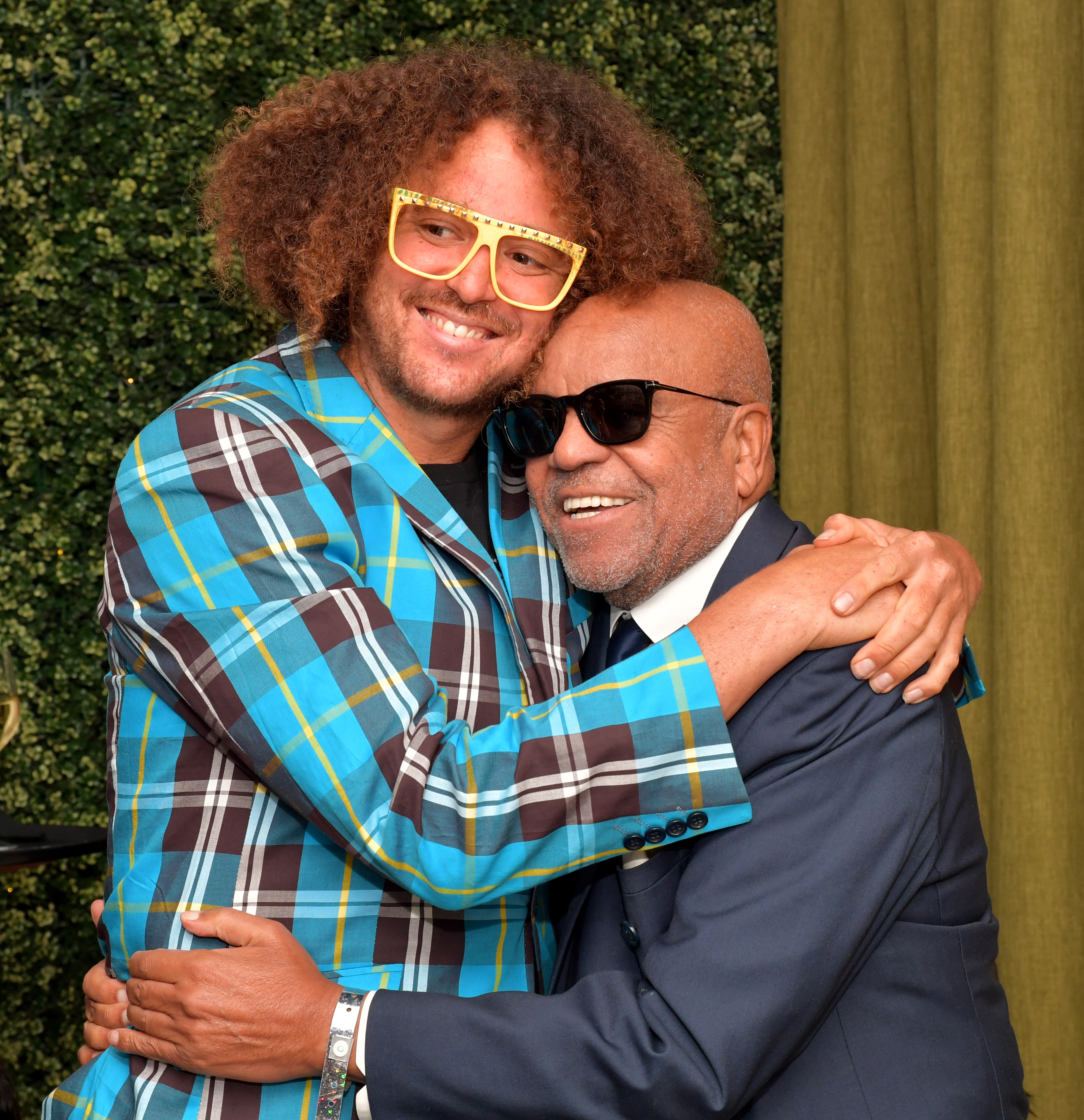 Redfoo, in a plaid suit jacket, hugs Berry Gordy, in a dark suit, both smiling at an event