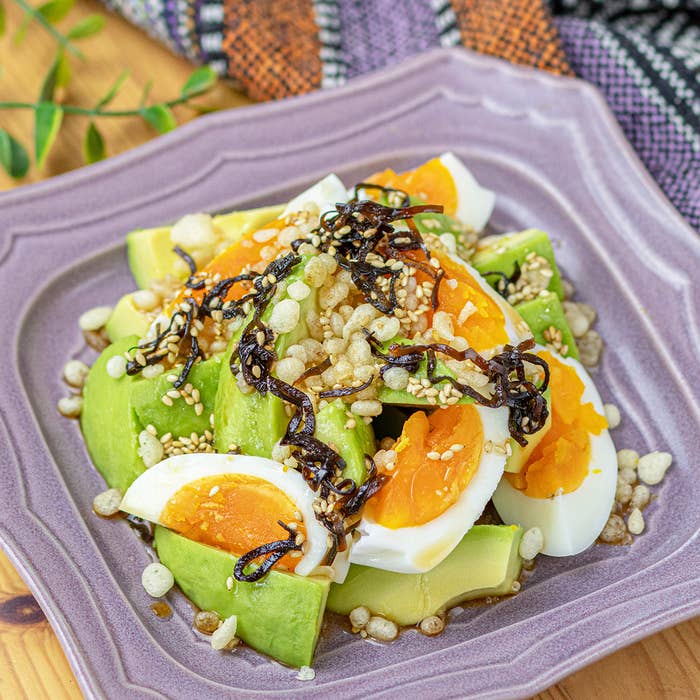 アボカドとゆで卵のサラダ、ゴマと塩昆布がトッピングされた料理。