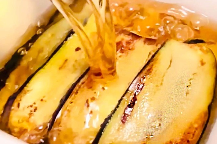 ナスのスライスにソースをかけているクローズアップ写真です。