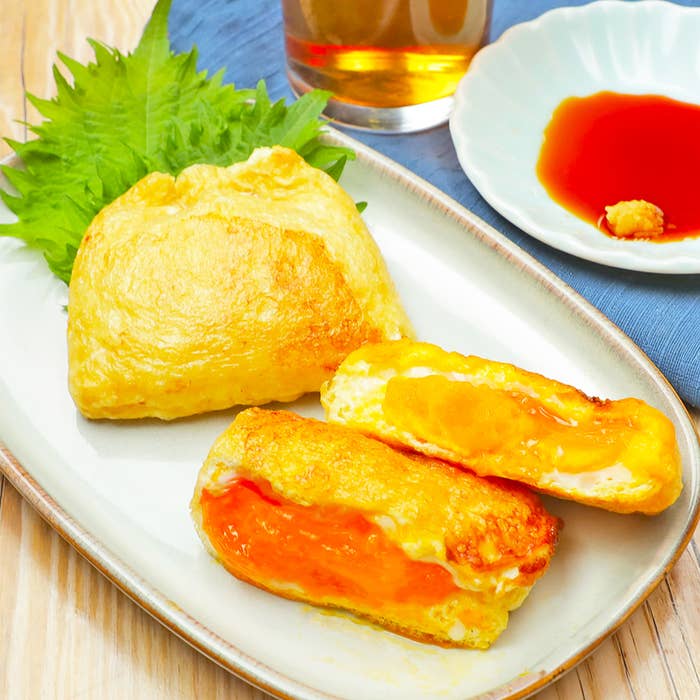 お皿に盛られた料理と付け合わせのシソ、横には醤油とおろし生姜の入った小皿とグラスがある。