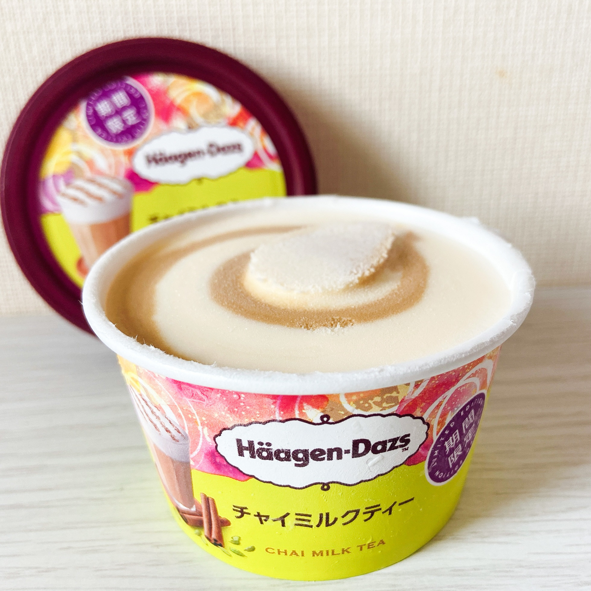 ハーゲンダッツのチャイミルクティーフレーバーのアイスクリーム容器。背景に同じ商品が写っています。