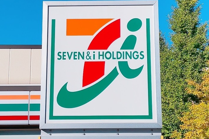 セブン&amp;アイ・ホールディングスのロゴが描かれた看板。背景には建物と木が見える。
