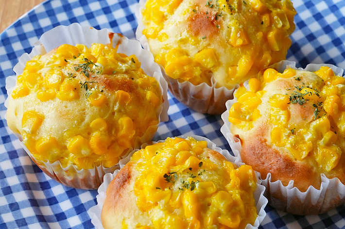 青白のチェック柄の皿の上にコーンマフィンが4つ並んでいます。