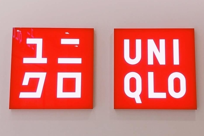 Red and white UNIQLO store signs on a wall, with text in Japanese characters on the left and English on the right