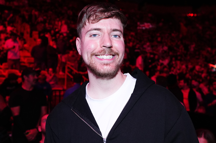 A man in casual attire smiles at a crowded event venue