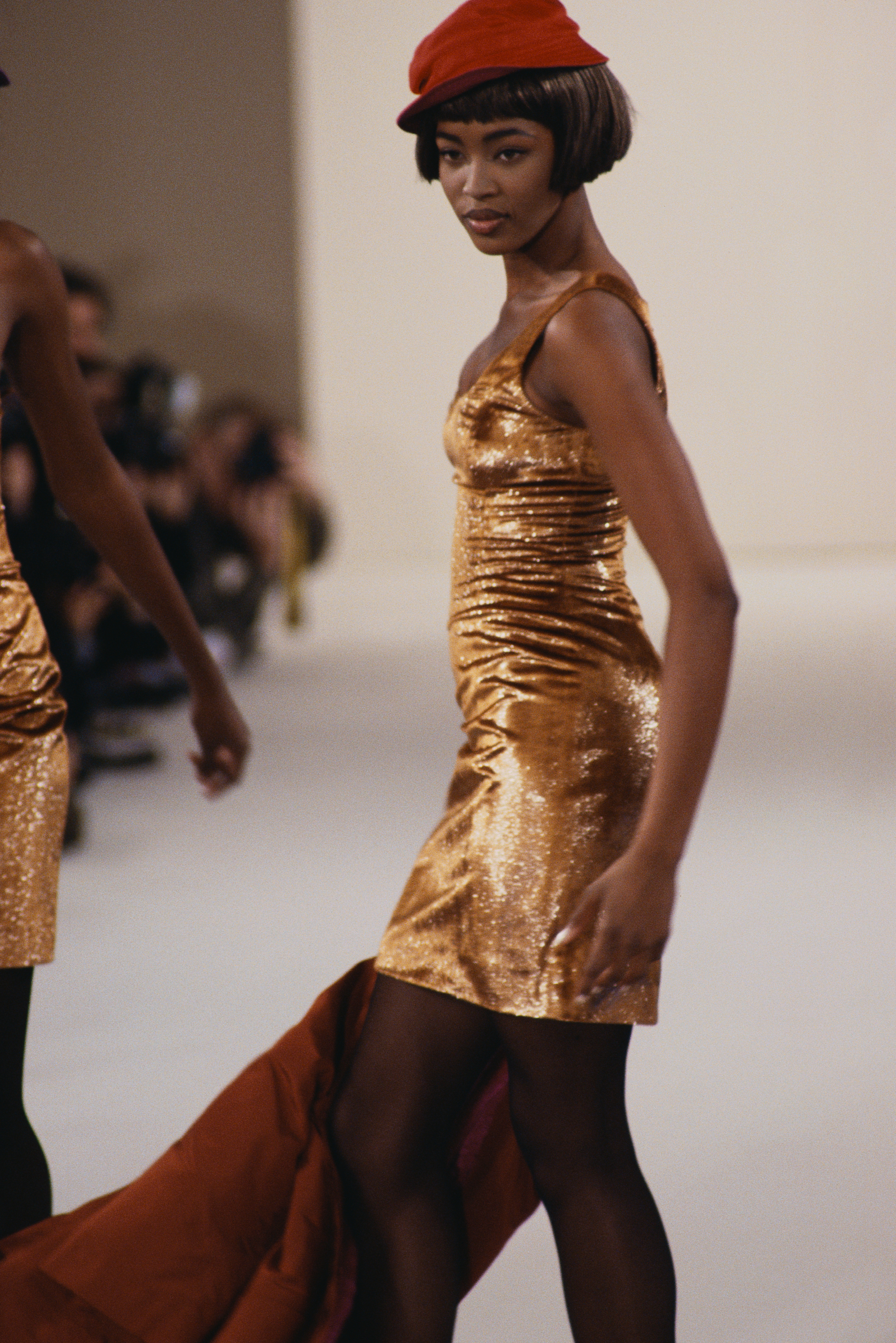 A teen Naomi Campbell walks the runway in a shimmering dress and beret