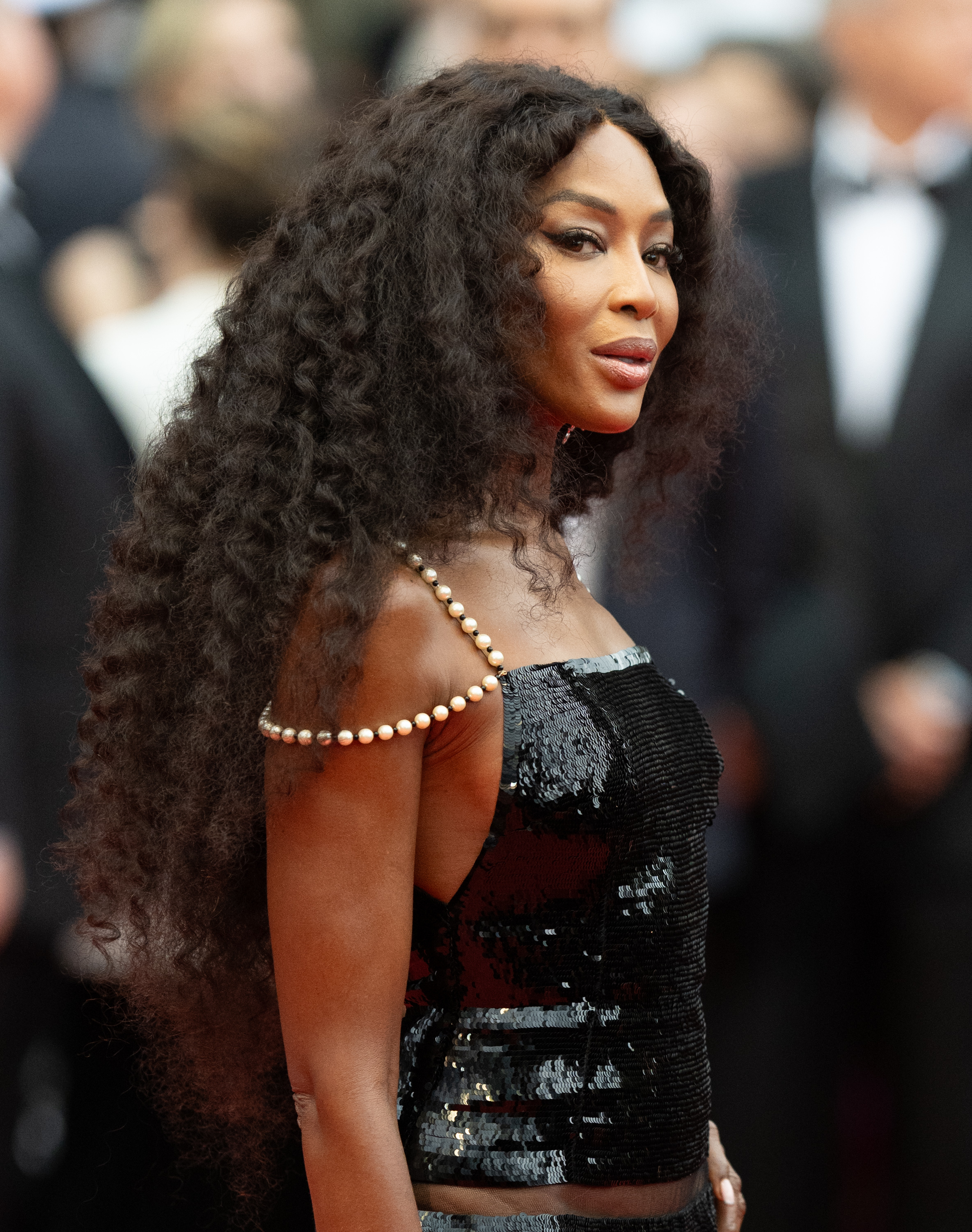 Naomi Campbell on the red carpet in a sleek, sequined dress adorned with pearls